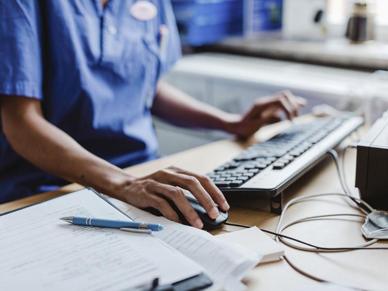 Health care worker using computer at desk in hospital 