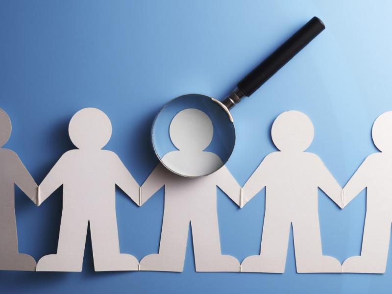 Paper figures with a magnifying glass over one