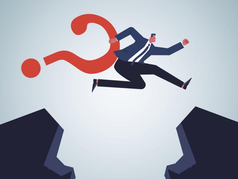 Businessperson holding a question mark leaps over a crevasse