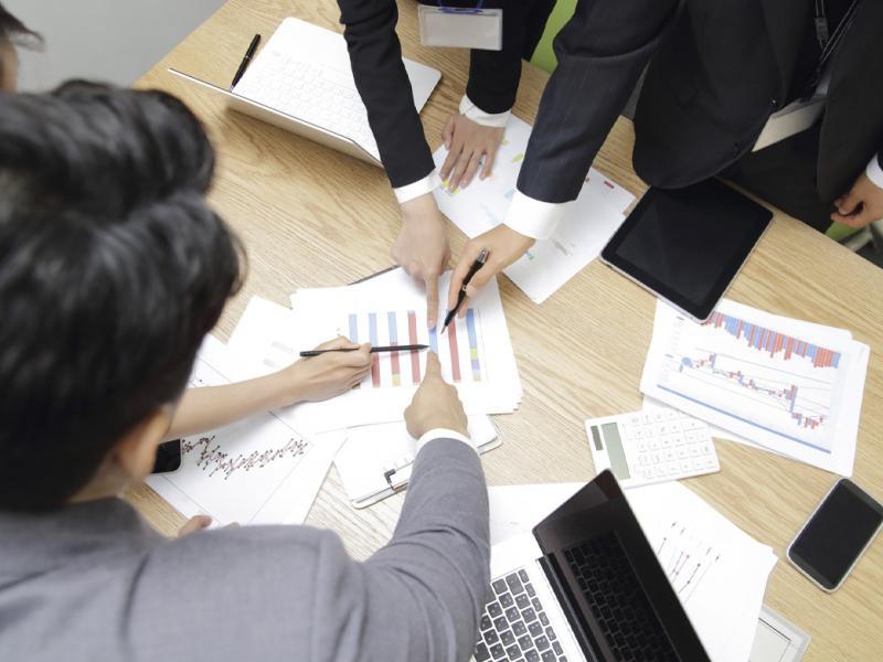 Businesspeople point to one place with pen and finger