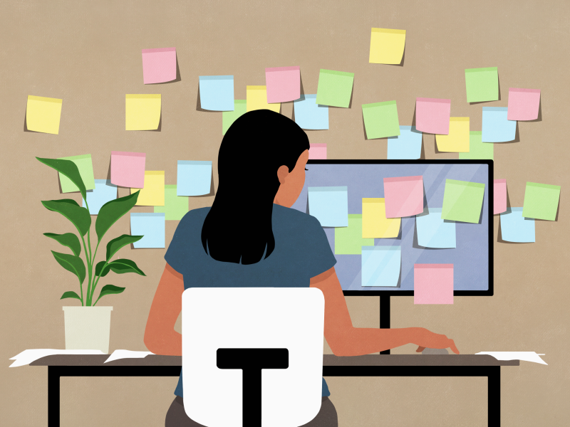  Sticky notes covering computer and wall in front of businesswoman working at desk