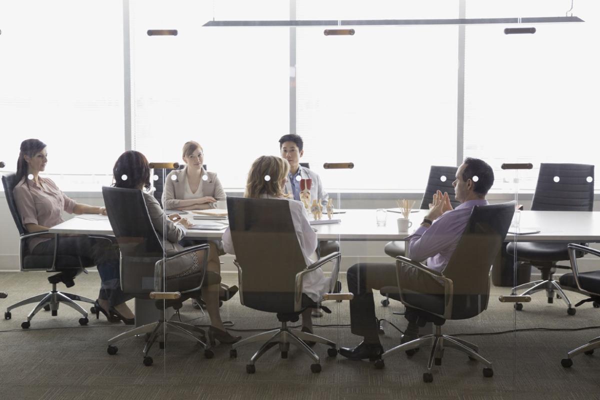 Six adults sitting around a conference room table