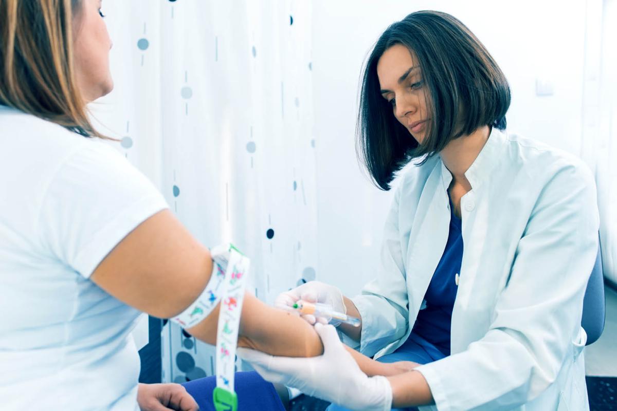 Female doctor taking blood sample from female patient