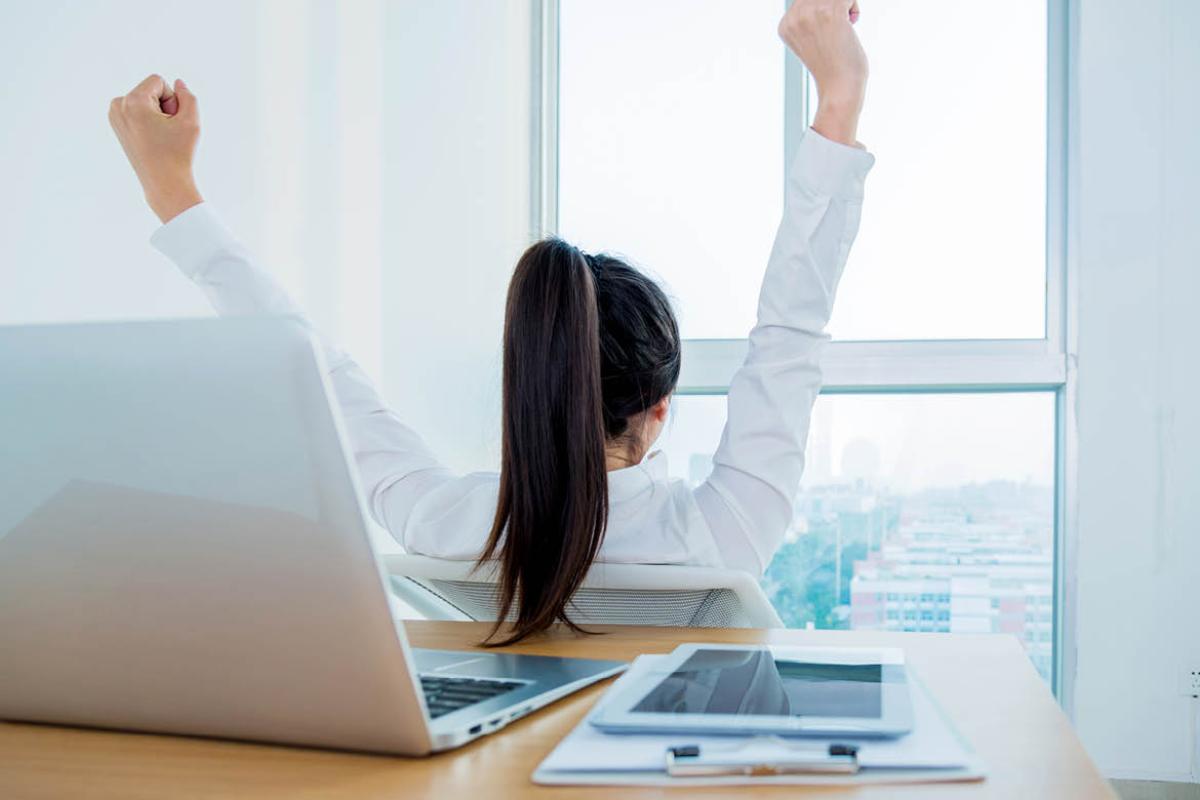 Woman at a computer with arms raised