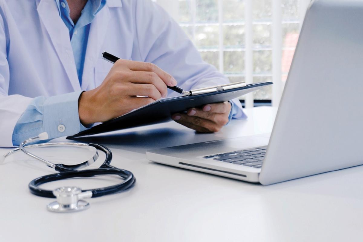Physician writing on a clipboard at their desk