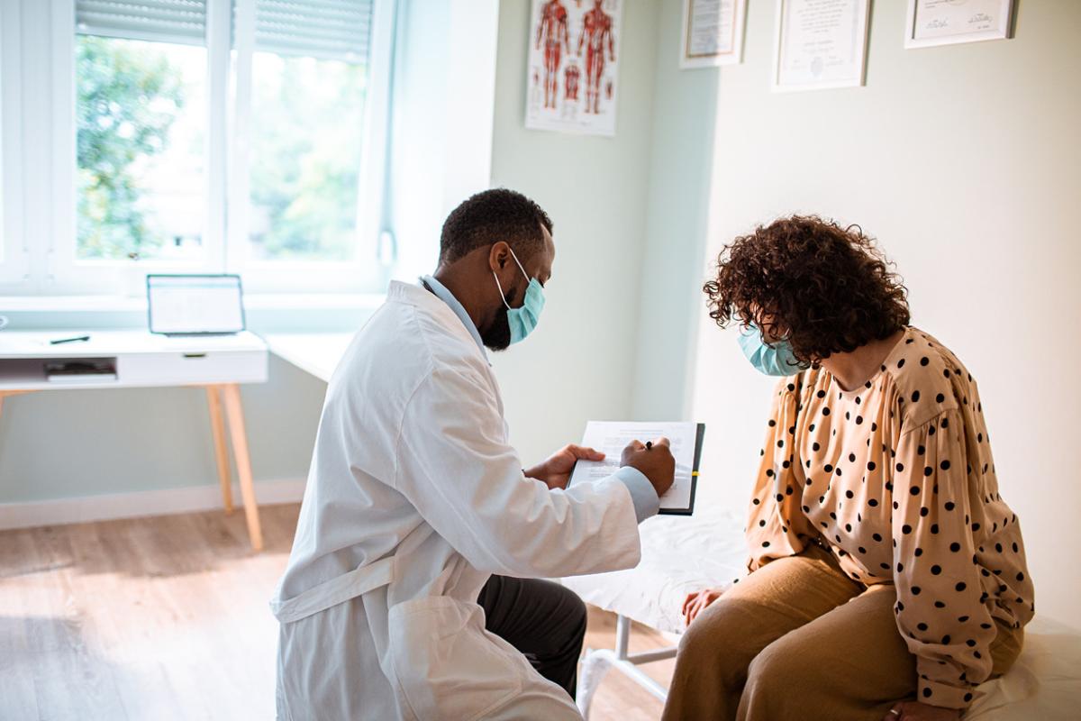 Masked doctor speaking with masked patient