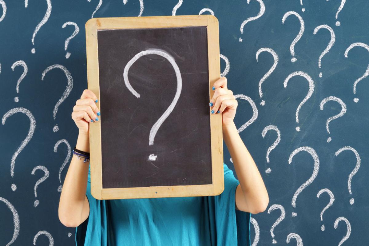 Person holing a chalk board with a question mark on it