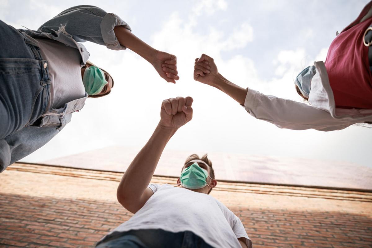 Three people fist bumping