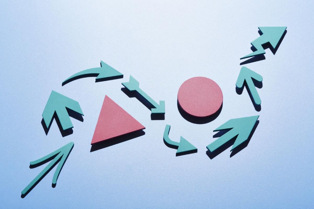 A series of light blue arrows of different shapes and design making an s-curve around a pink triangle and pink circle.
