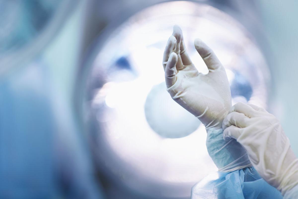 Surgeon adjusting gloves in operating room