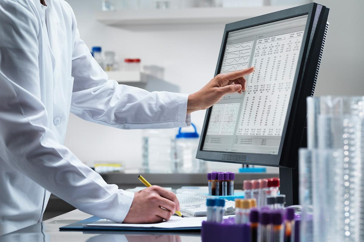 Health care worker at computer and pointing at screen