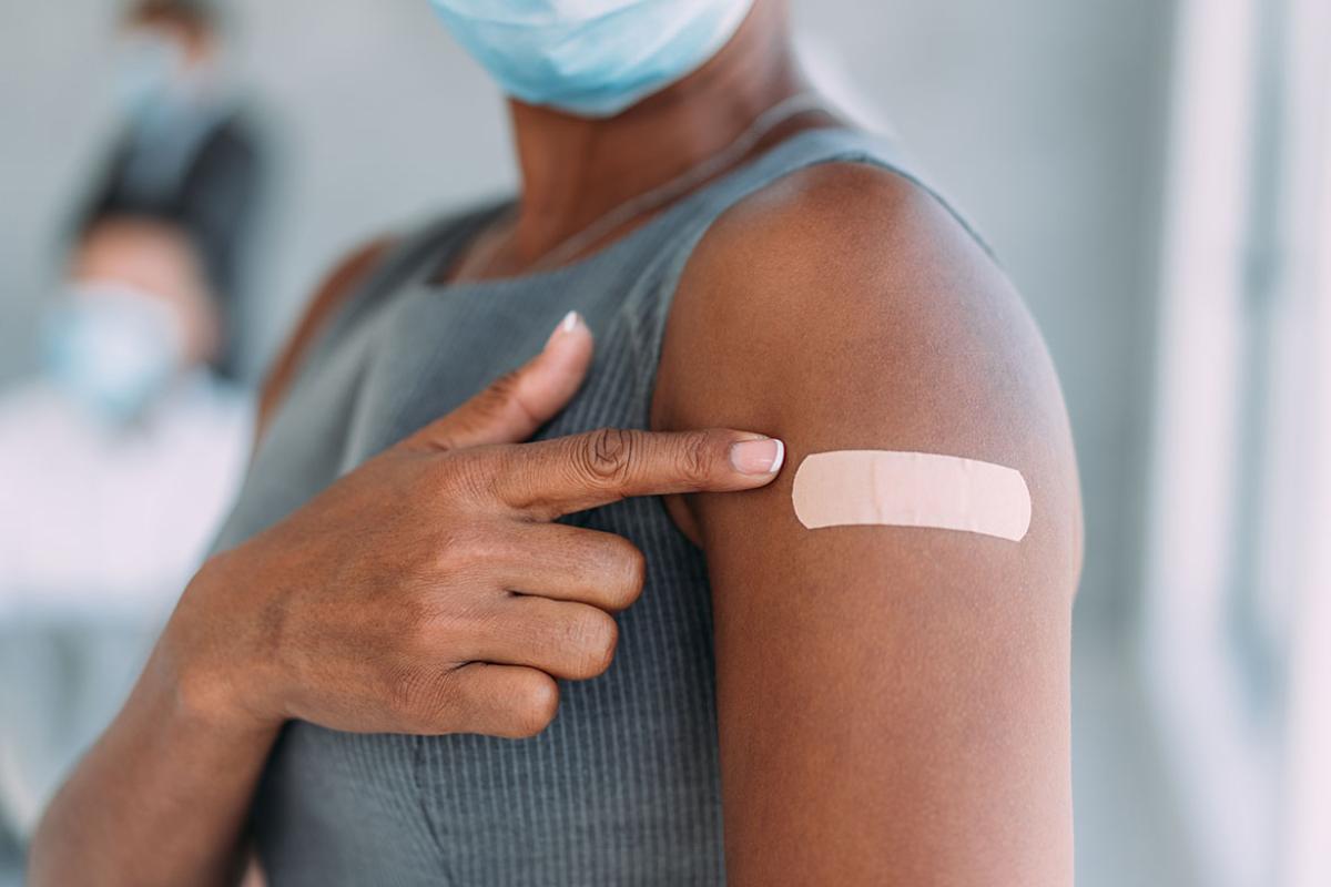 Person pointing at bandage on upper arm