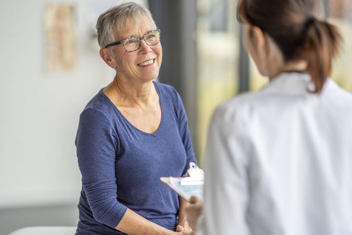 Patient sits up on an exam table during a health check-up with doctor