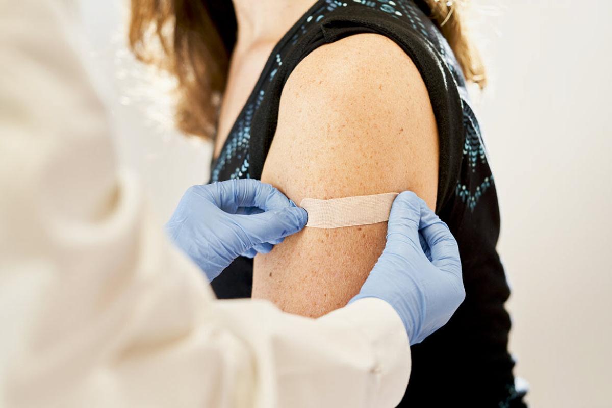 Physician applying bandage to patient arm