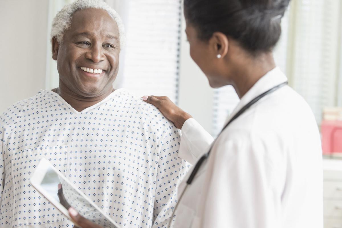 Physician places hand on smiling patient's shoulder