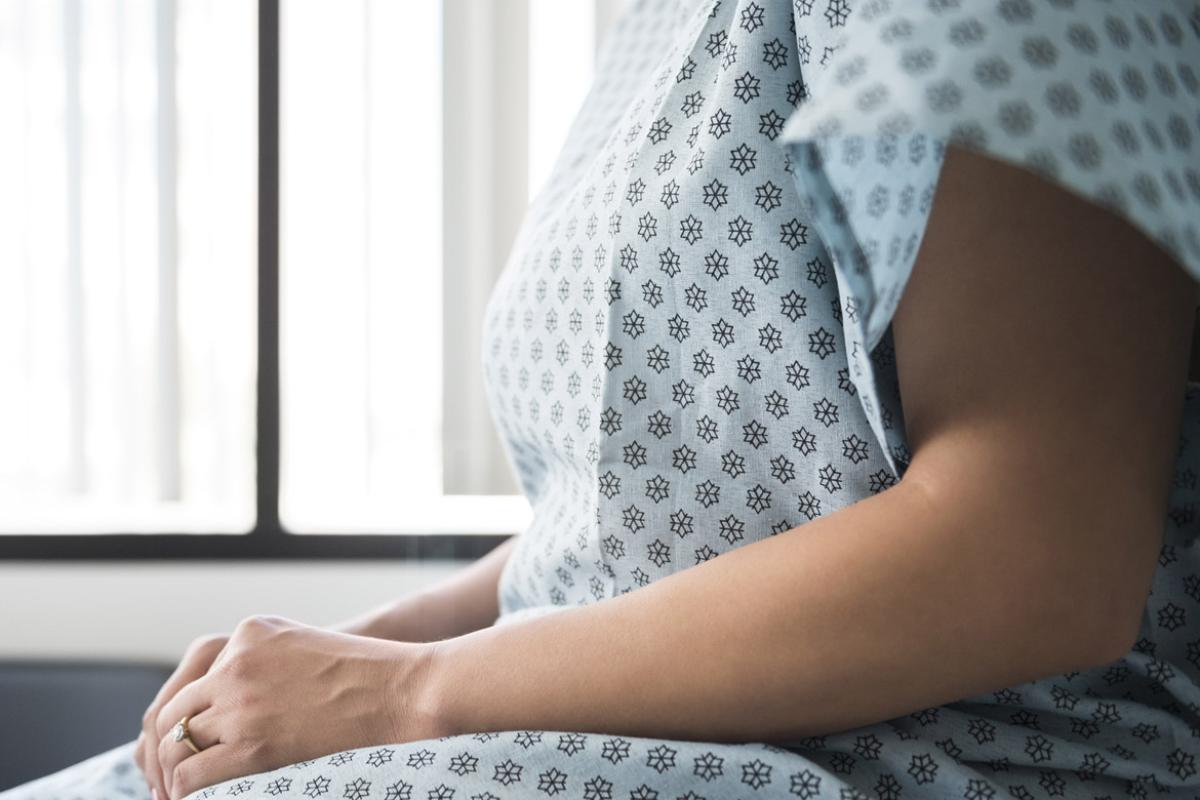 Midsection of patient in hospital gown waiting in exam room
