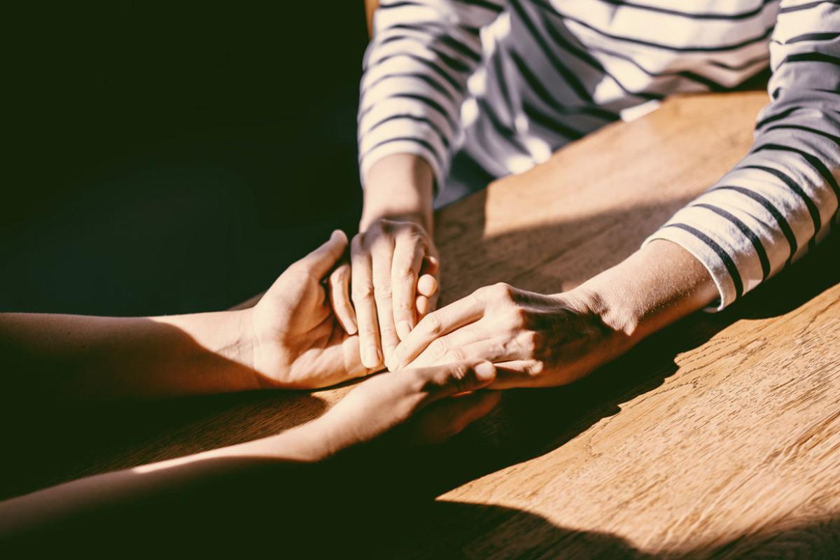 Two people at a table hold hands