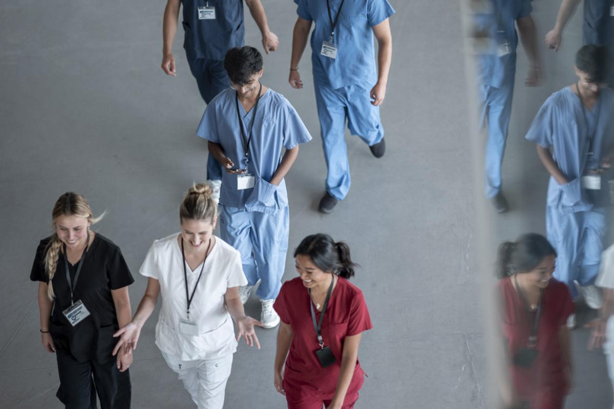 Smiling health care workers converse in a busy hallway