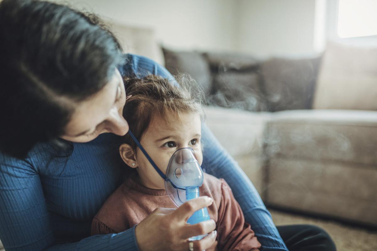 Parent helps young child use inhaler