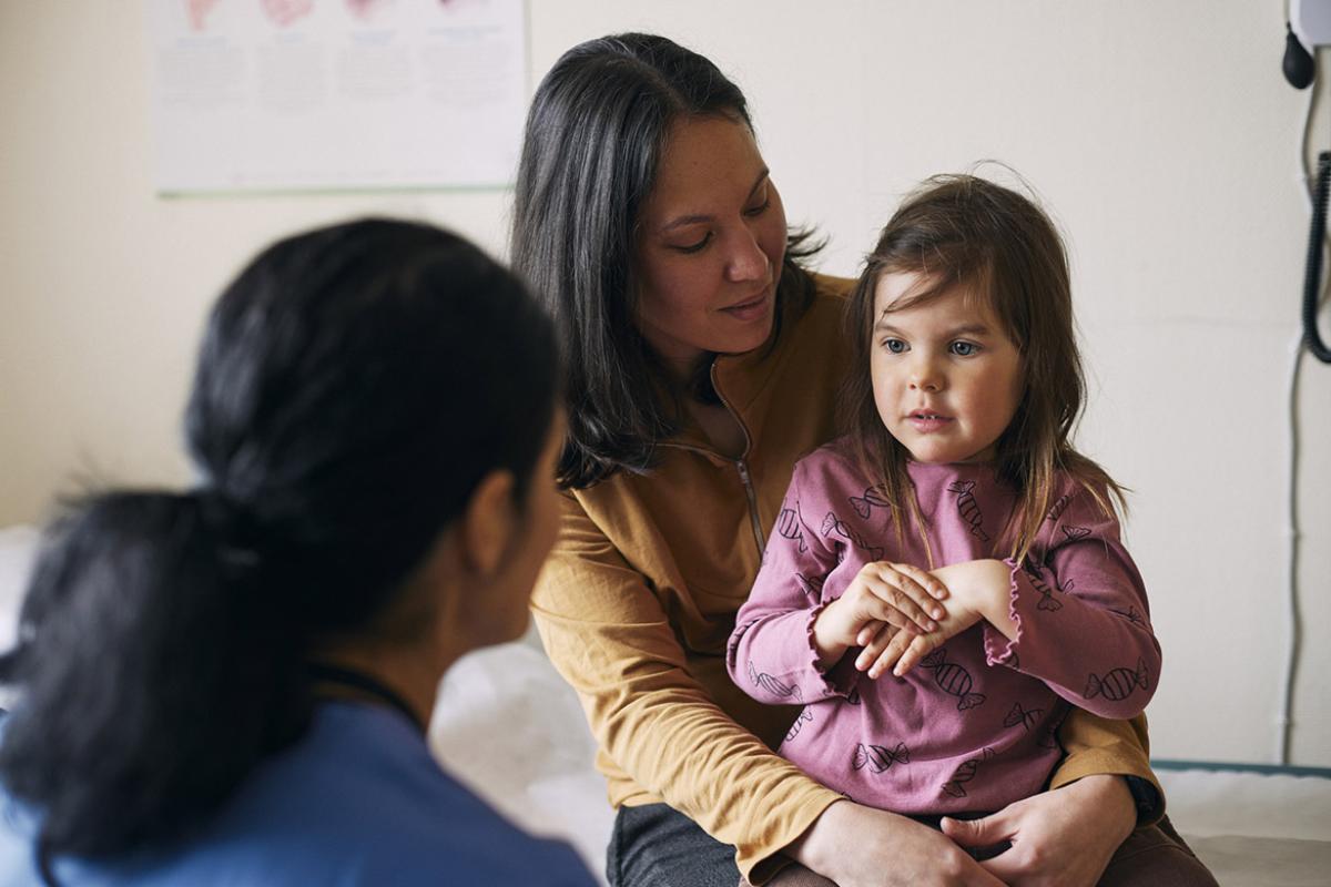 Parent holds young child during doctor's appointment