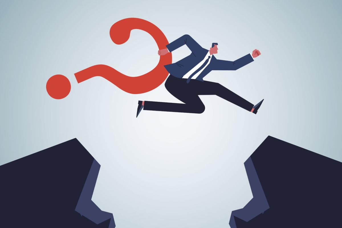 Businessperson holding a question mark leaps over a crevasse