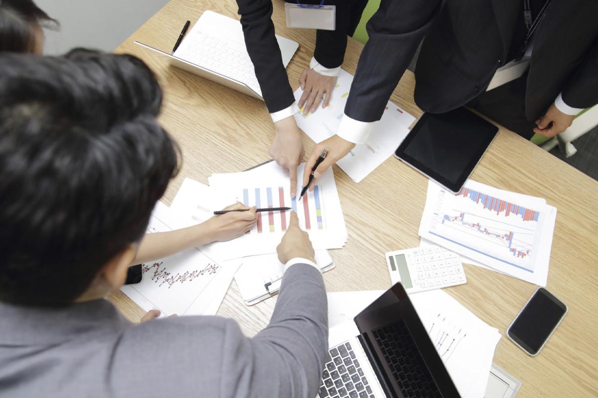 Businesspeople point to one place with pen and finger