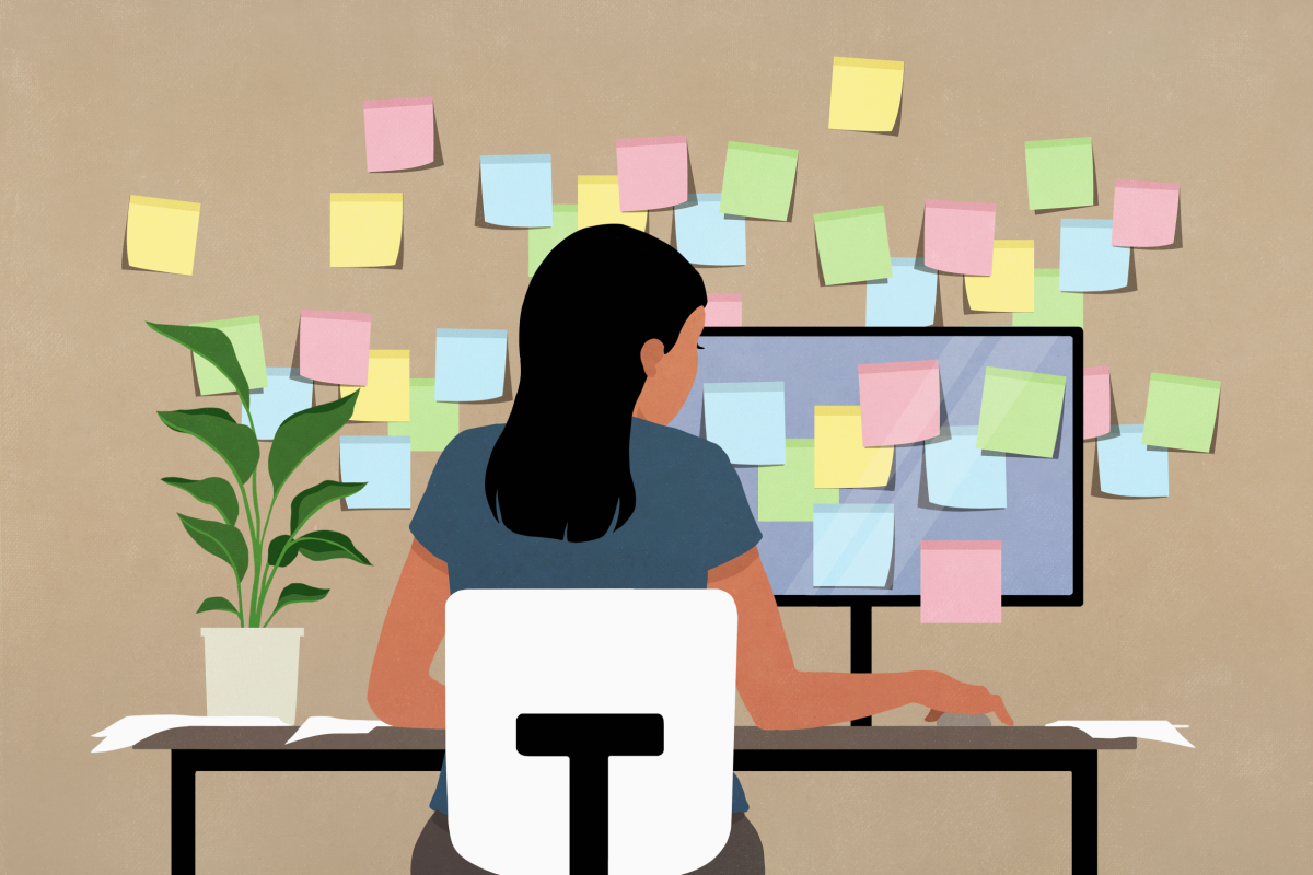  Sticky notes covering computer and wall in front of businesswoman working at desk