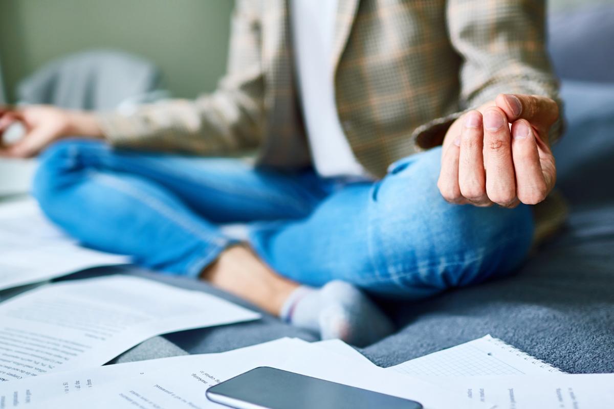 A student meditating amidst a number of papers surrounding them 