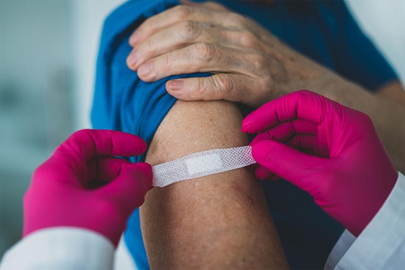 Gloved hands placing a bandage on a person's arm